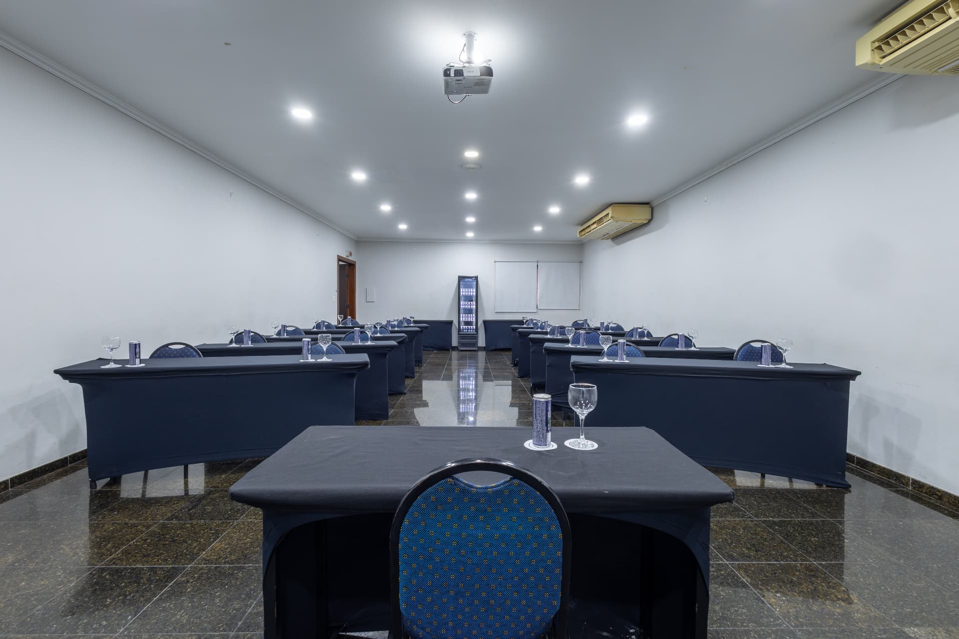 Sala de reunião com projetor e mesas montadas para treinamento